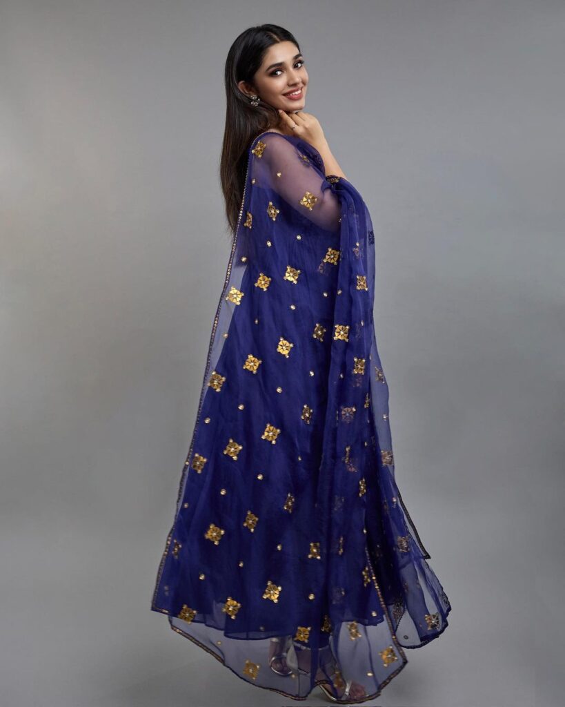 A beautiful anarkali suit in blue, adorned with exquisite gold embroidery, worn by Krithi Shetty.
