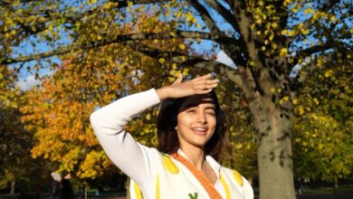 featuring Pooja Hegde, elegantly dressed in a sweater, standing amidst the beauty of a park.