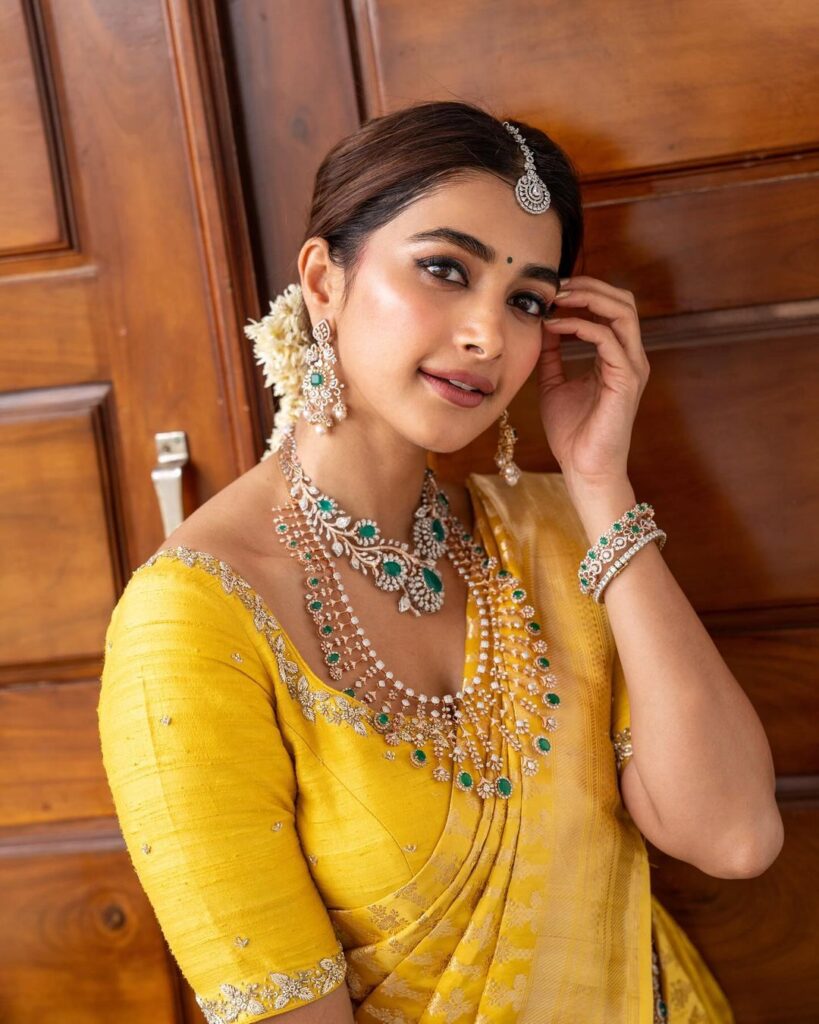 Pooja Hegde shines in a vibrant yellow pattu saree with green bead embellishments, complemented by a matching choukar