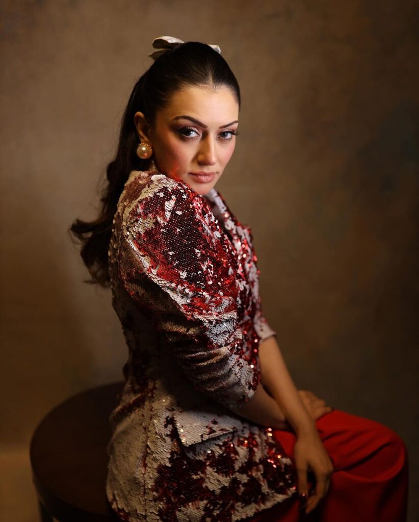 Hansika in a red bodycon dress, grey blazer, and silver heels