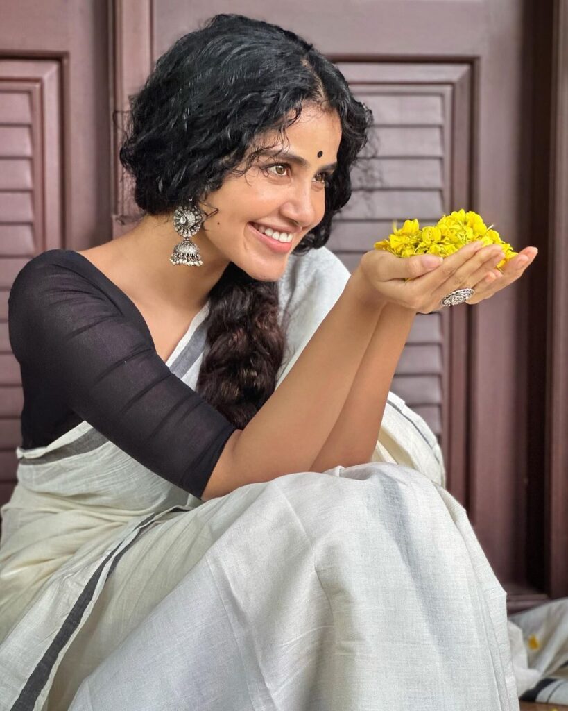 Anupama radiates grace in white saree, adorned with flowers, curly hair