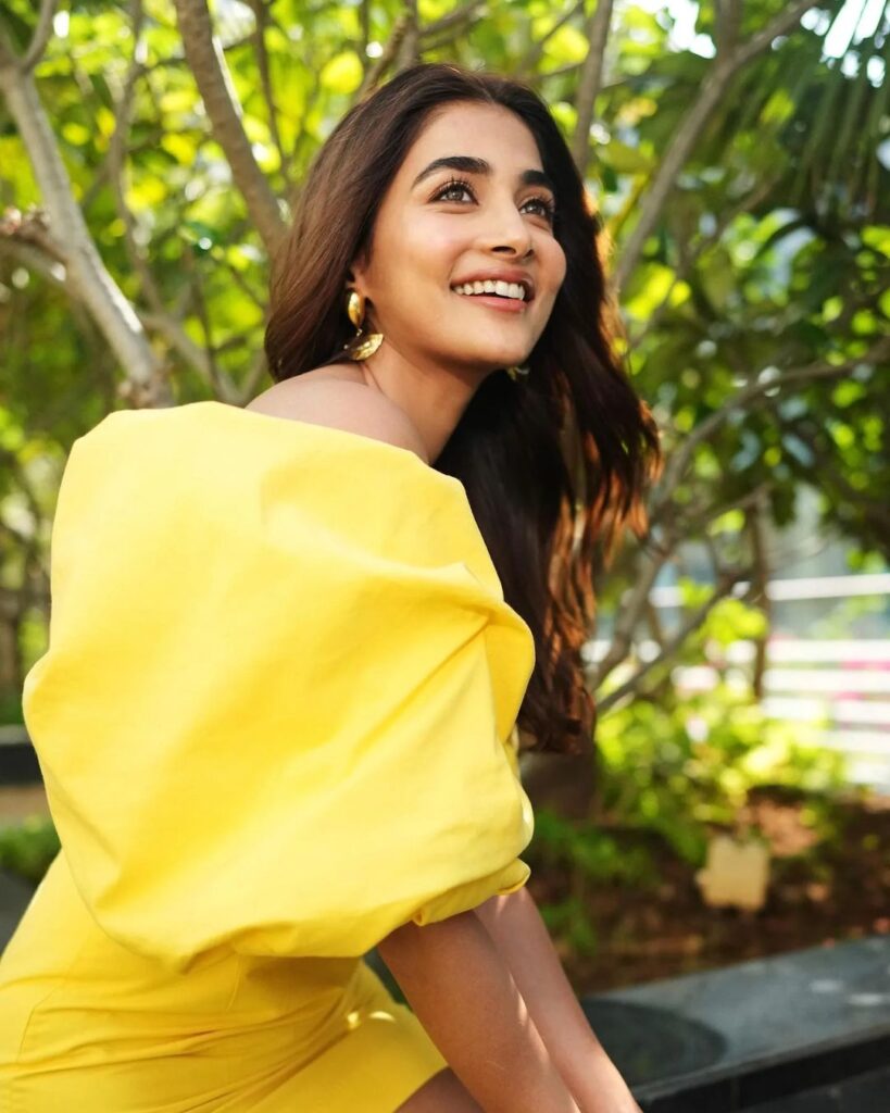 Pooja Hegde in yellow mini dress with flowing hair and bright smile